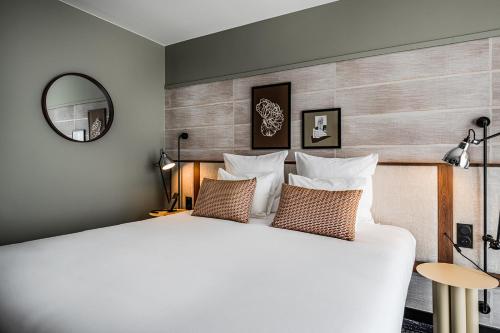 a bedroom with a large white bed and a mirror at Thalazur Carnac in Carnac