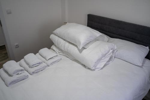 a white bed with white pillows and towels on it at Apartmani Novakovic in Velika Plana