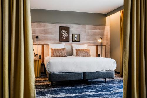a bedroom with a large bed and curtains at Thalazur Carnac in Carnac
