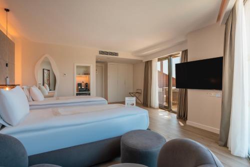 a hotel room with two beds and a flat screen tv at Qlusive Hotel in Kusadası