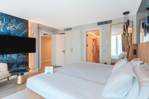 a bedroom with two beds and a flat screen tv at Qlusive Hotel in Kusadası