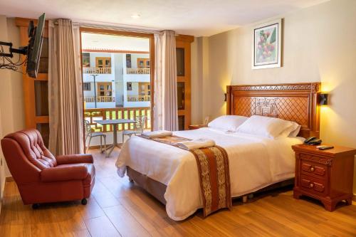 a bedroom with a bed and a chair and a balcony at Gran Kuntur Wasi Hotel Casa y Campo in Cajamarca
