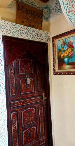 a wooden door in a room with a painting on the wall at Palais AL Firdaous in Fès