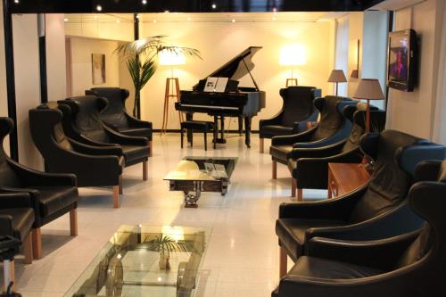 a waiting room with a grand piano and chairs at Hotel Miramonti in Schio
