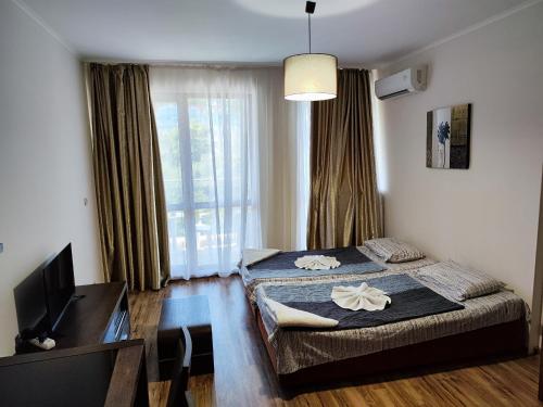 a bedroom with two beds and a desk and a television at Europroperties Golden Line in Golden Sands