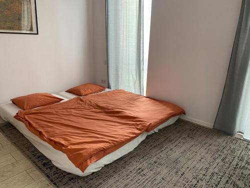 a bed with an orange comforter in a bedroom at Apartament Zoom 42 in Bydgoszcz