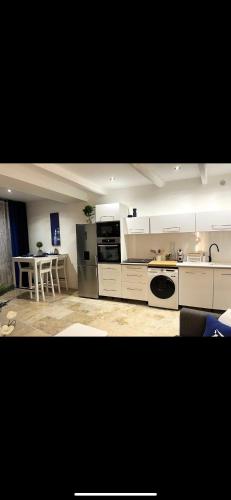 une cuisine avec des armoires blanches et une table à l'intérieur dans l'établissement Apparemment Résidence la palmeraie, à Lapalme