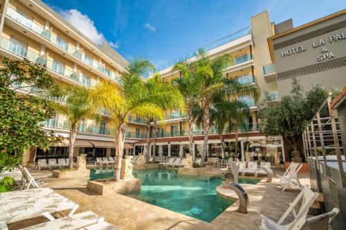 a hotel with a swimming pool in front of a building at Hotel la Palmera & Spa in Lloret de Mar