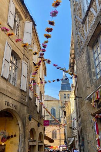 une rue avec des bâtiments avec des drapeaux de prière et une église dans l'établissement Au cœur du centre historique de Sarlat, à Sarlat-la-Canéda