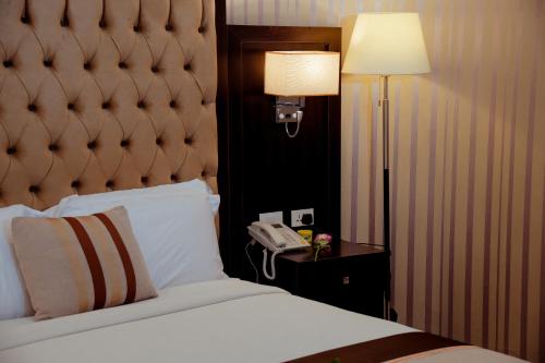 a bedroom with a bed and a lamp and a phone at 泊悦国际大酒店 BoYue Hotel in Addis Ababa Bole International Airport