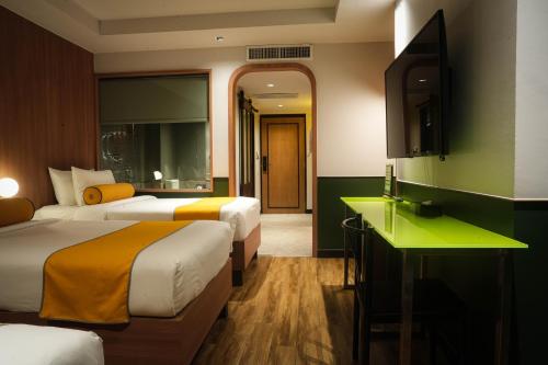 a hotel room with two beds and a television at Graph Hotels Bangkok in Bangkok