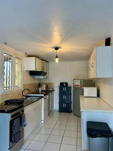 une cuisine avec des placards blancs et un plafond dans l'établissement Charmant bas de villa avec jardin, à La Ciotat