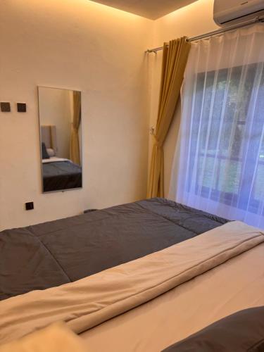 a bedroom with a bed with a mirror and a window at Villa TUWAIQ 1 فيلا طويق بونشاك in Sampal 2