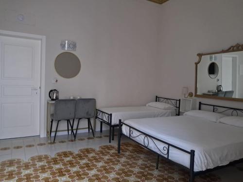 a room with two beds and a table and a mirror at Asmundo Palace Suites & Spa in Catania