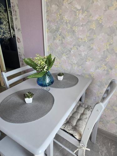 a white table with two chairs and a vase of flowers at Kate Sea Apartment in Pärnu