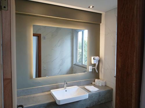 a bathroom with a sink and a large mirror at Pousada Cantares in Tiradentes