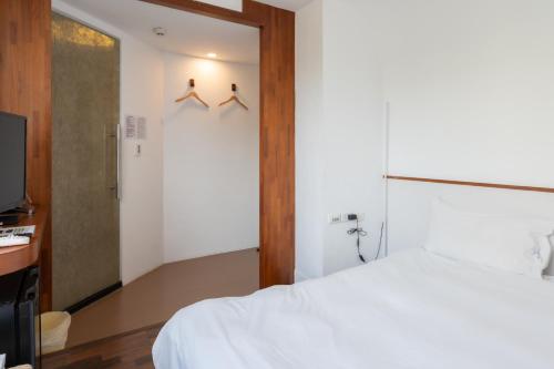 a bedroom with a white bed and a sliding door at 日日藍旅市區民宿 in Hualien City