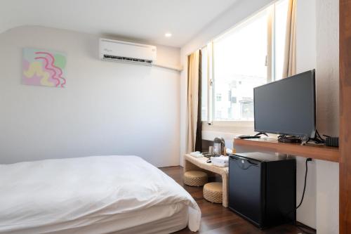 a bedroom with a bed and a television on a desk at 日日藍旅市區民宿 in Hualien City