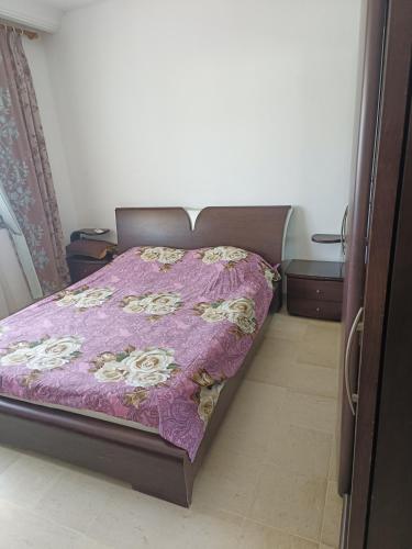 a bed in a room with a purple bedspread at Marwan in Tunis