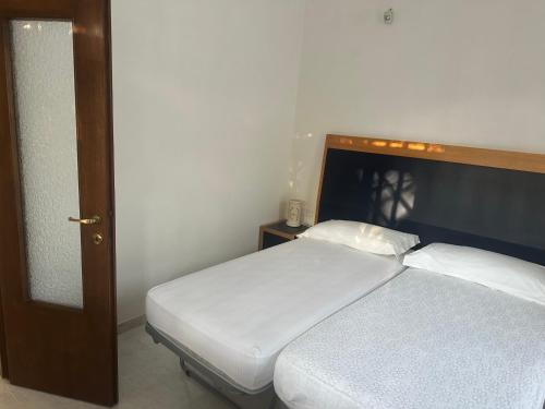 1 dormitorio con 1 cama con sábanas blancas y cabecero de madera en DefensolaRelax, en Vieste