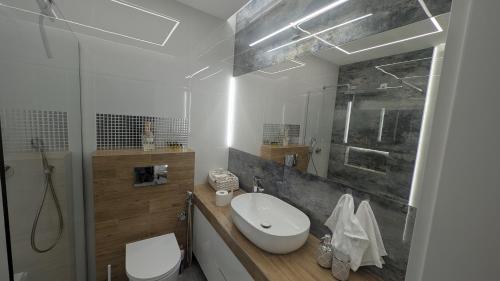 a white bathroom with a sink and a toilet at Apartament ROYAL Ełk in Ełk