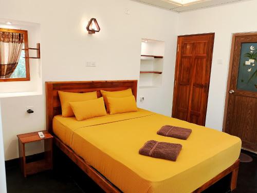 a bedroom with a yellow bed with two towels on it at Milk House Cottage in Udawalawe