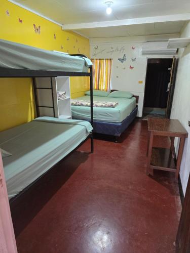 a room with two bunk beds and a table at Congos Hostal y Camping in Playa Hermosa