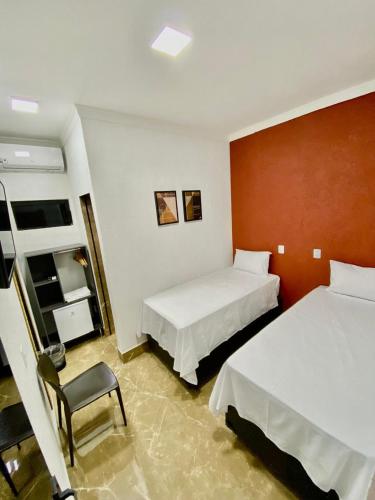 una camera d'albergo con due letti e una sedia di Hotel Uirapuru 02 a Alexânia