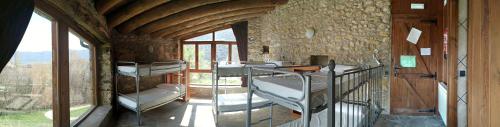 a room with several bunk beds in a stone building at Albergue Casa Fumenal in Padarniu