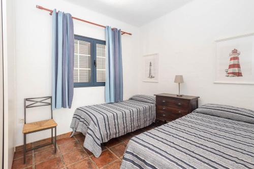 a bedroom with two beds and a chair and a window at Lightbooking La Graciosa in Caleta de Sebo