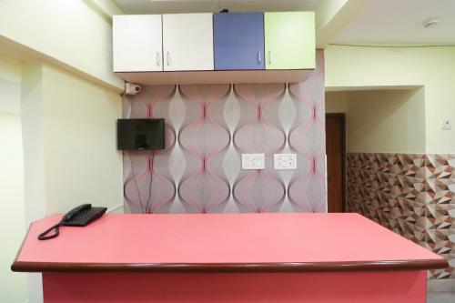 a red counter in a room with a phone on it at Hotel O Home Cozy Studio Collage Square Hotel Maya International Near St. Thomas's Church in Kolkata