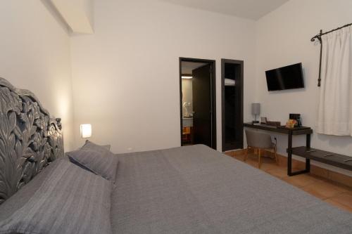 a bedroom with a bed and a desk and a television at Hotel Boutique Naura Centro in Oaxaca City