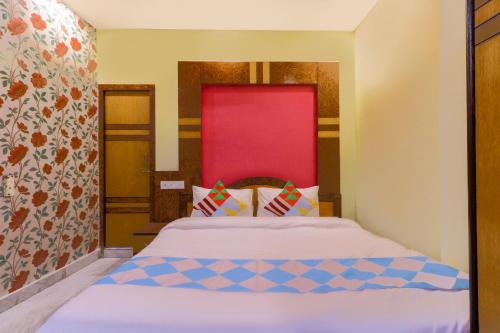 a bedroom with a bed with a red headboard at Hotel O Home Cozy Studio Collage Square Hotel Maya International Near St. Thomas's Church in Kolkata