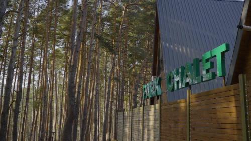a sign in front of a forest of tall trees at Park Hotel Surami Chalet in Surami