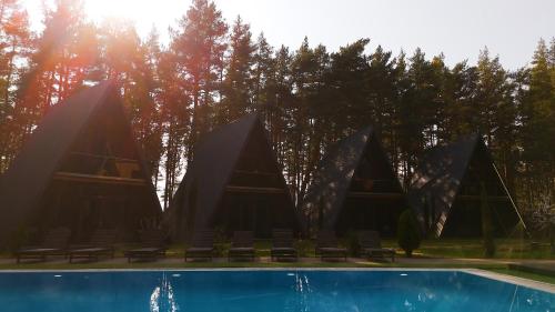 a building with a swimming pool with chairs and trees at Park Hotel Surami Chalet in Surami