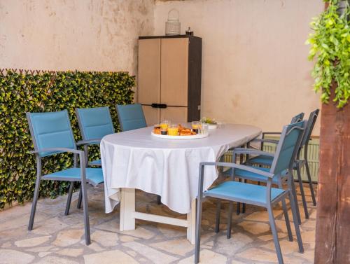 une table blanche avec des chaises bleues et un réfrigérateur dans l'établissement Charmant 4 pièces - Cour privative - Port de Nice, à Nice