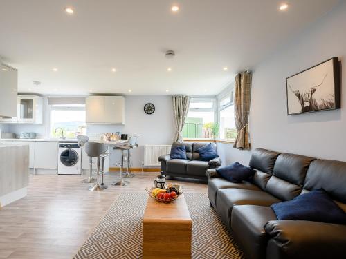 a living room with a leather couch and a kitchen at Sand View in Mainsriddle