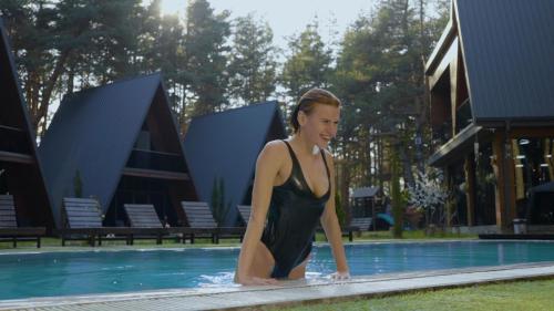 a woman in a swimsuit standing in a swimming pool at Park Hotel Surami Chalet in Surami