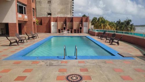 a large swimming pool with chairs and a table at TUCACAS VISTA Y SALIDA AL MAR Apto TIPO ESTUDIO DUPLEX SIN HABITACIÓN INDEPENDIENTE in Tucacas