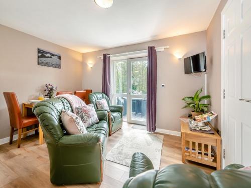 a living room with two green chairs and a table at Owl Cottage in Llandeilo