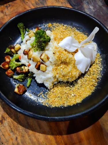 a black plate of food with rice and broccoli at Finca La Selvita Chocolate experience in Buritaca