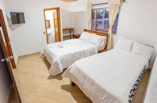 two beds in a room with a window at Hotel Macizo Tiaguanaco in San Agustín