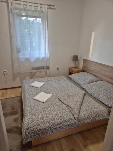 two beds in a bedroom with a window and two towels at Apartmany-Anna in Podhájska