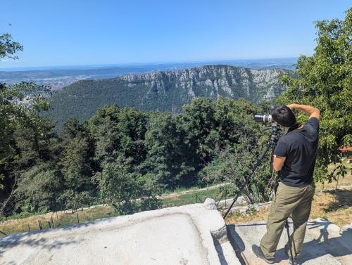 a man taking a picture of the mountains with a camera at Prenočišča Center Mir In Dobro in Solkan