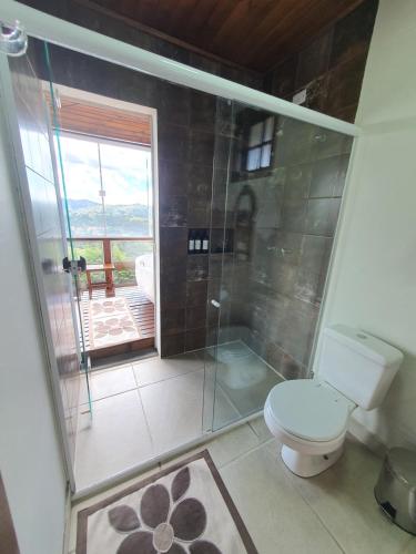 a bathroom with a toilet and a glass shower at Chalé 3 com Hidro Acima das Nuvens in Campos do Jordão