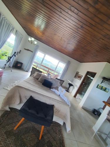 a bedroom with a large bed and a large window at Chalé 3 com Hidro Acima das Nuvens in Campos do Jordão