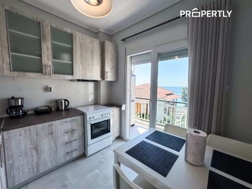 a kitchen with a table and a stove and a window at Blue Seaview Apartment #PROPERTLY in Nea Kalikratia