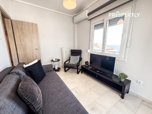 a living room with a couch and a flat screen tv at Blue Seaview Apartment #PROPERTLY in Nea Kalikratia