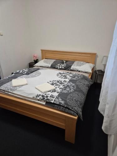 a bed with a black and white comforter on it at Apartmany-Anna in Podhájska