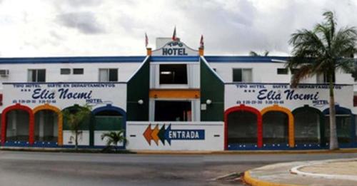 a white and blue building with a palm tree at Hotel Suites Elia Noemi in Mérida